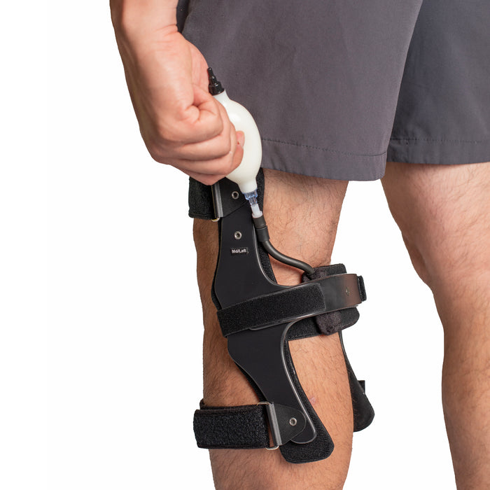 Close-up of an OCSI OrthoPro HyperEx Knee Brace being adjusted with its manual pump.
