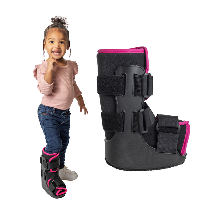 A smiling girl demonstrates the fit of the green Brace Direct Pediatric Walker Fracture Boot, beside a side view of the boot in pink.