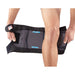 Man demonstrates how to fit the Breg FreeSport Athletic Knee Support Brace, step 1: place the brace behind the knee.