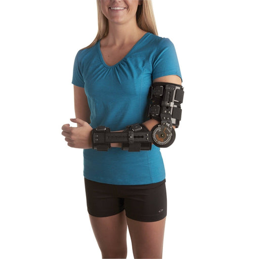 A smiling woman demonstrates the fit of the Breg T-Chek Adjustable Elbow Brace, by Brace Direct.