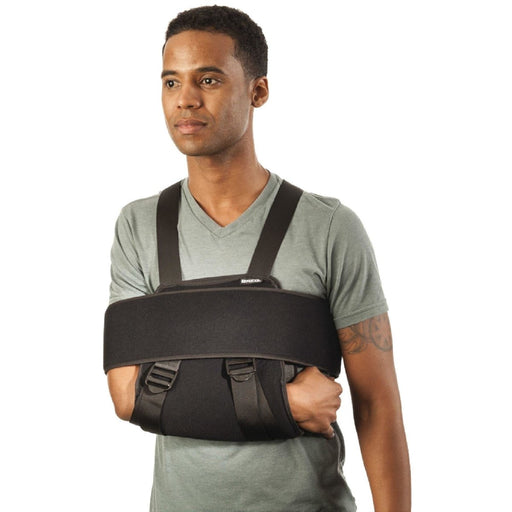 A male model demonstrates the fit of the Breg Universal Sling and Swathe, by Brace Direct.